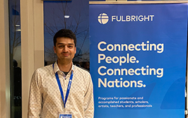 Moeez posing in front of Fulbright sign that says, "Connecting people. Connecting nations."