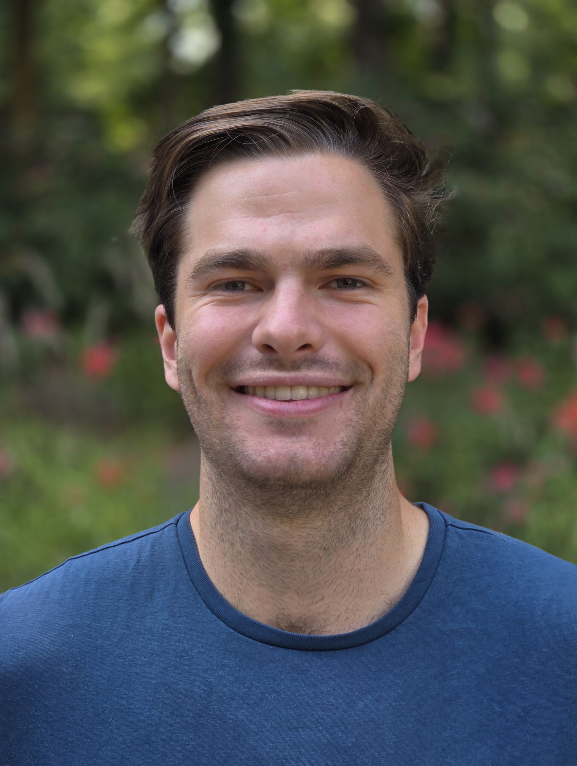 A headshot of Jay in a blue shirt, outside.