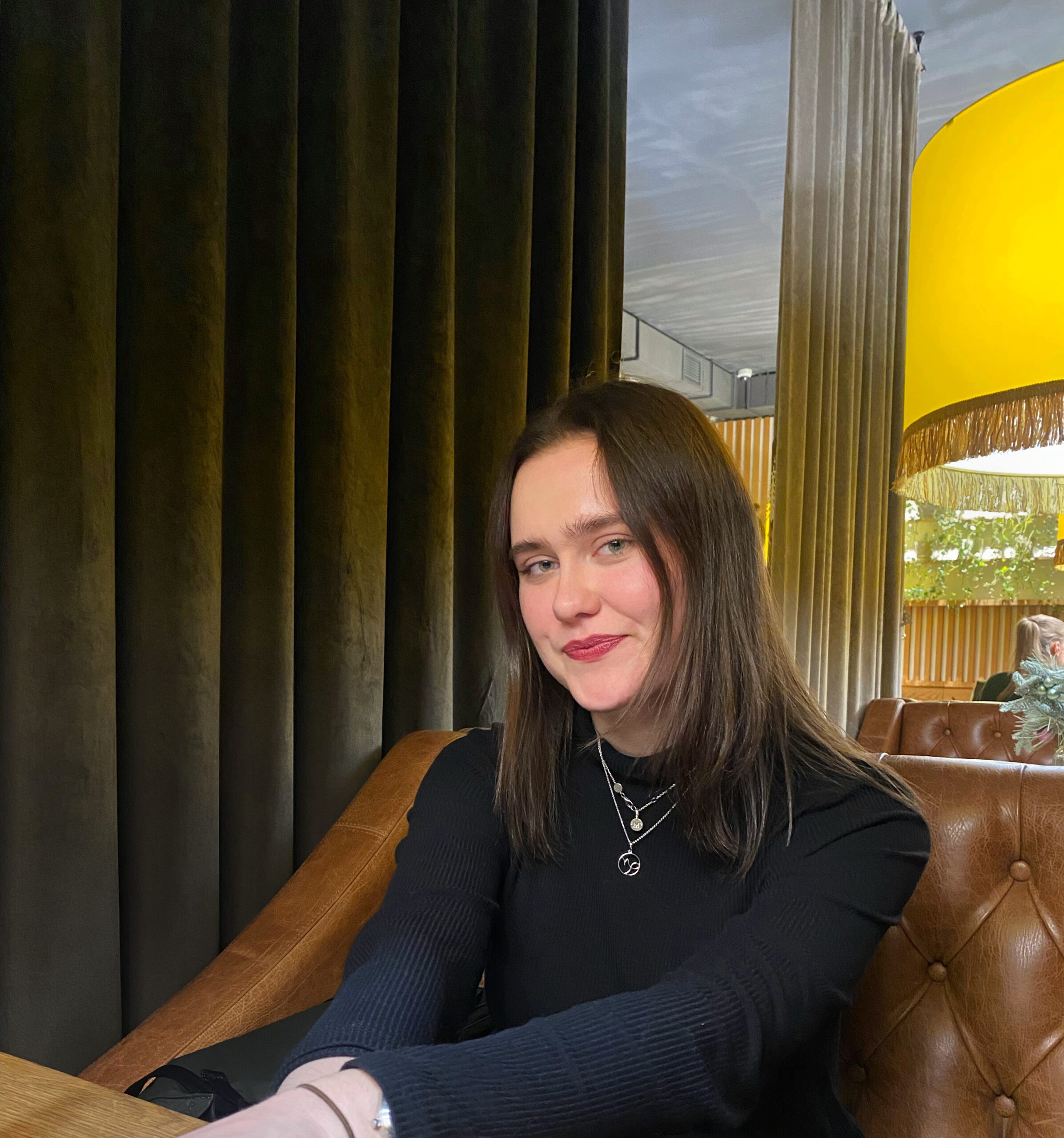 Photo of Mariya in a dark turtle neck sitting on a leather couch