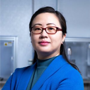 Jie Xiao in a blue blazer posing in a classroom